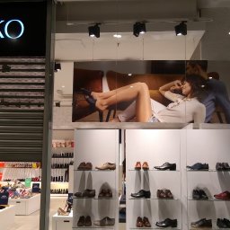 Engage Media - Witryna sklepu obuwniczego Ryłko z plakatem reklamowym przedstawiającym leżącą modelkę i ekspozycją butów na półkach. Część witryny zasłonięta roletą.