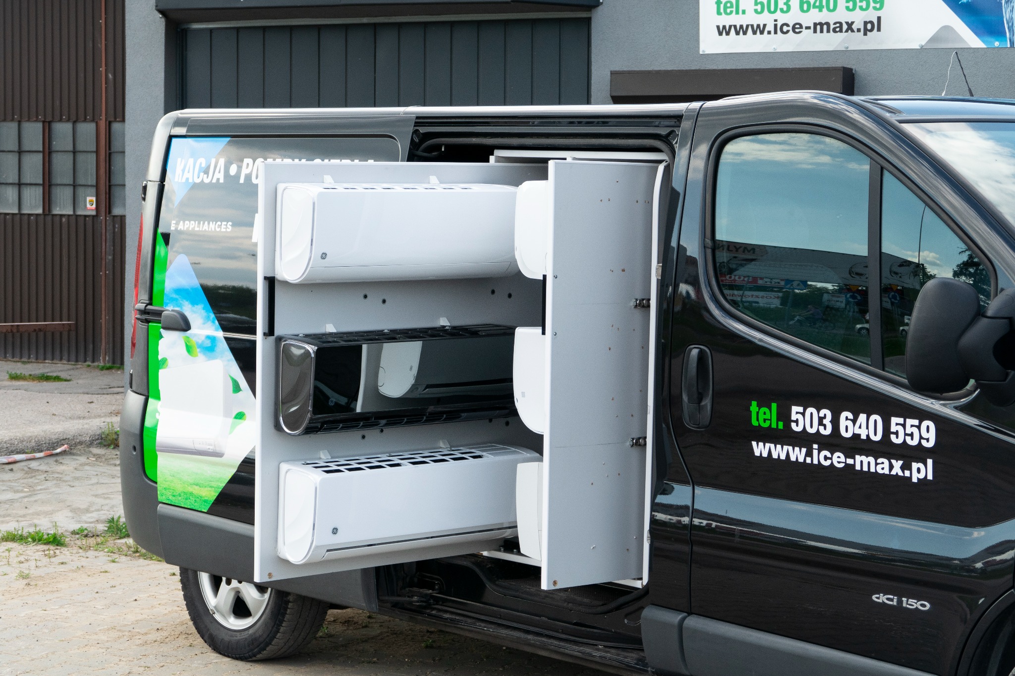 Czarny van z otwartymi drzwiami, prezentujący klimatyzatory na półkach wewnątrz. Widoczne logo firmy i numer telefonu na karoserii.