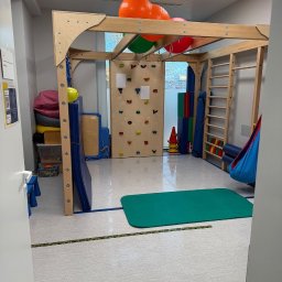 Piotr STARK - Sala sensoryczna z drabinkami, ścianką wspinaczkową i kolorowymi piłkami. Widok zza progu, czysta podłoga, jasne oświetlenie.