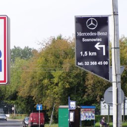 SCAN MOTOPOL SPÓŁKA Z OGRANICZONĄ ODPOWIEDZIALNOŚCIĄ - Czarny szyld Mercedes-Benz w Sosnowcu, 1,5 km w lewo, numer telefonu. W tle zieleń drzew i szyld Aldi. Ulica z samochodami i przystanek autobusowy.