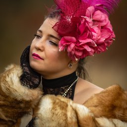 Patryk Kołodziejczyk - Portret kobiety w bogatym stroju z piórami i futrem, stylizowany na epokę. Makijaż i biżuteria podkreślają charakter sesji. Delikatne światło.