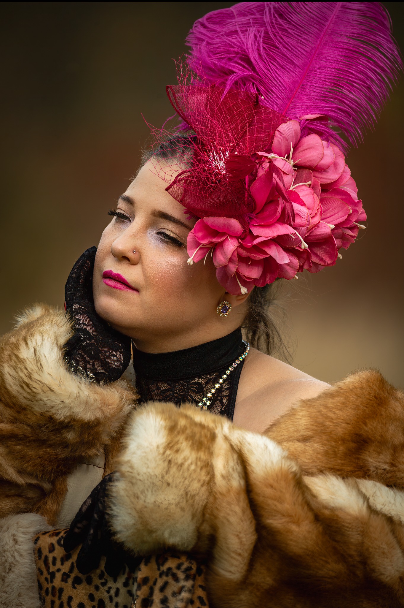 Portret kobiety w bogatym stroju z piórami i futrem, stylizowany na epokę. Makijaż i biżuteria podkreślają charakter sesji. Delikatne światło.