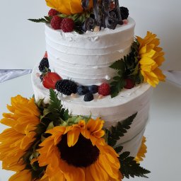 Tichy Sp.z o.o. - Dwupoziomowy tort z białym kremem, dekorowany słonecznikami, malinami, jeżynami i borówkami. Na górze czekoladowy napis '18'.