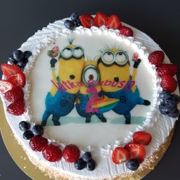 Tichy Sp.z o.o. - Tort urodzinowy z motywem Minionków, udekorowany bitą śmietaną i świeżymi owocami: truskawkami, malinami i borówkami. Na torcie napis 'Iatka Kubusia'.
