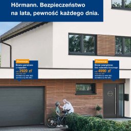 PIENIAK SPÓŁKA Z OGRANICZONĄ ODPOWIEDZIALNOŚCIĄ - Szara brama garażowa segmentowa z napędem i ciemne drzwi zewnętrzne bez naświetla bocznego, na tle elewacji domu z drewnianymi panelami. Kobieta z dzieckiem przy rowerze.