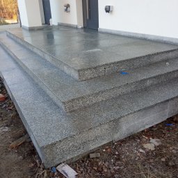 Yrek Horhus - Granitowe schody zewnętrzne prowadzące do wejścia budynku, wykończone z dbałością o detale, z widoczną fakturą kamienia i elementami wykończeniowymi.