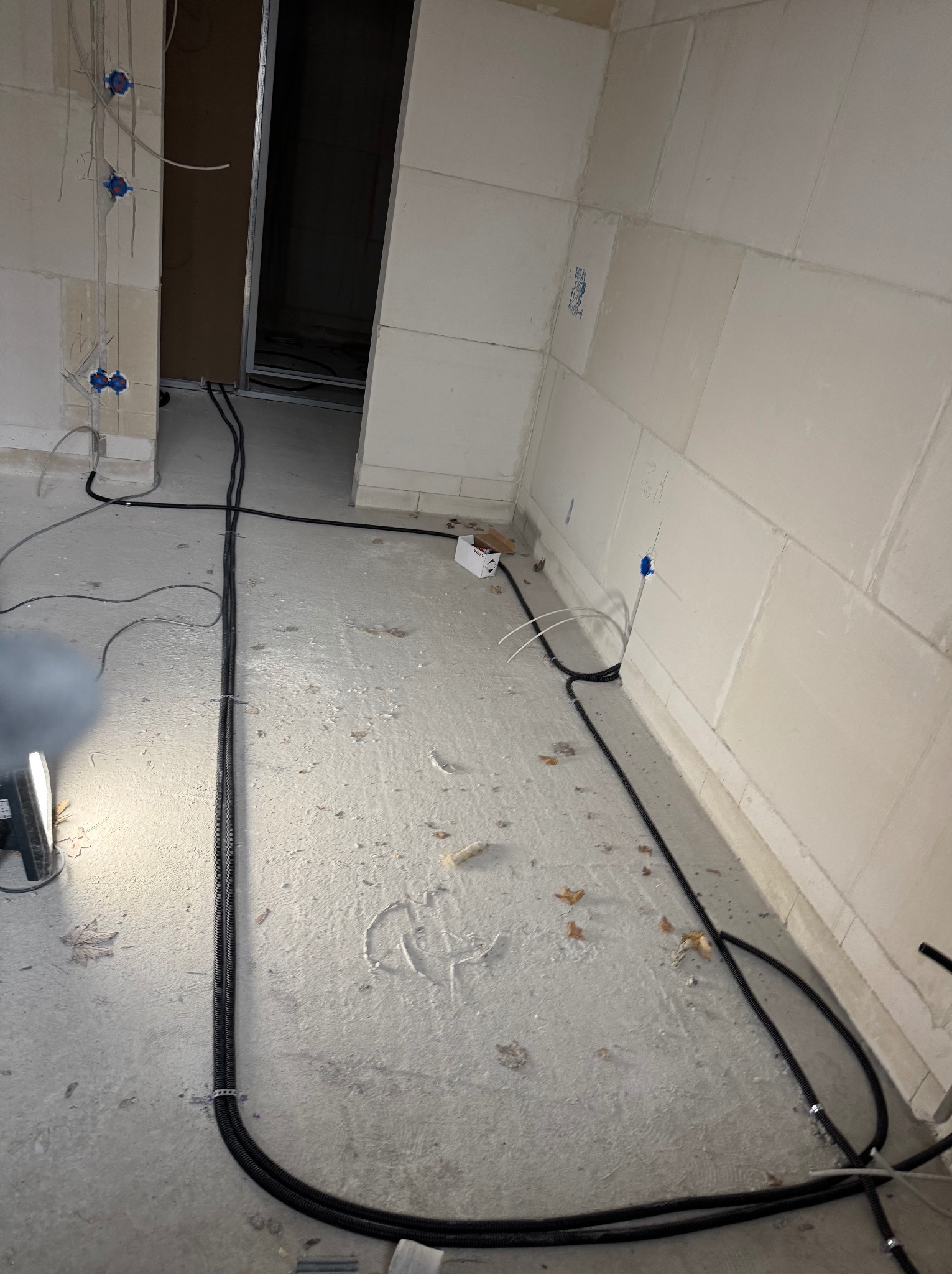 Rozprowadzone kable w peszlach na podłodze i wyprowadzone gniazdka w ścianach w trakcie prac w Chociwel. Widoczne kable i puszki instalacyjne.