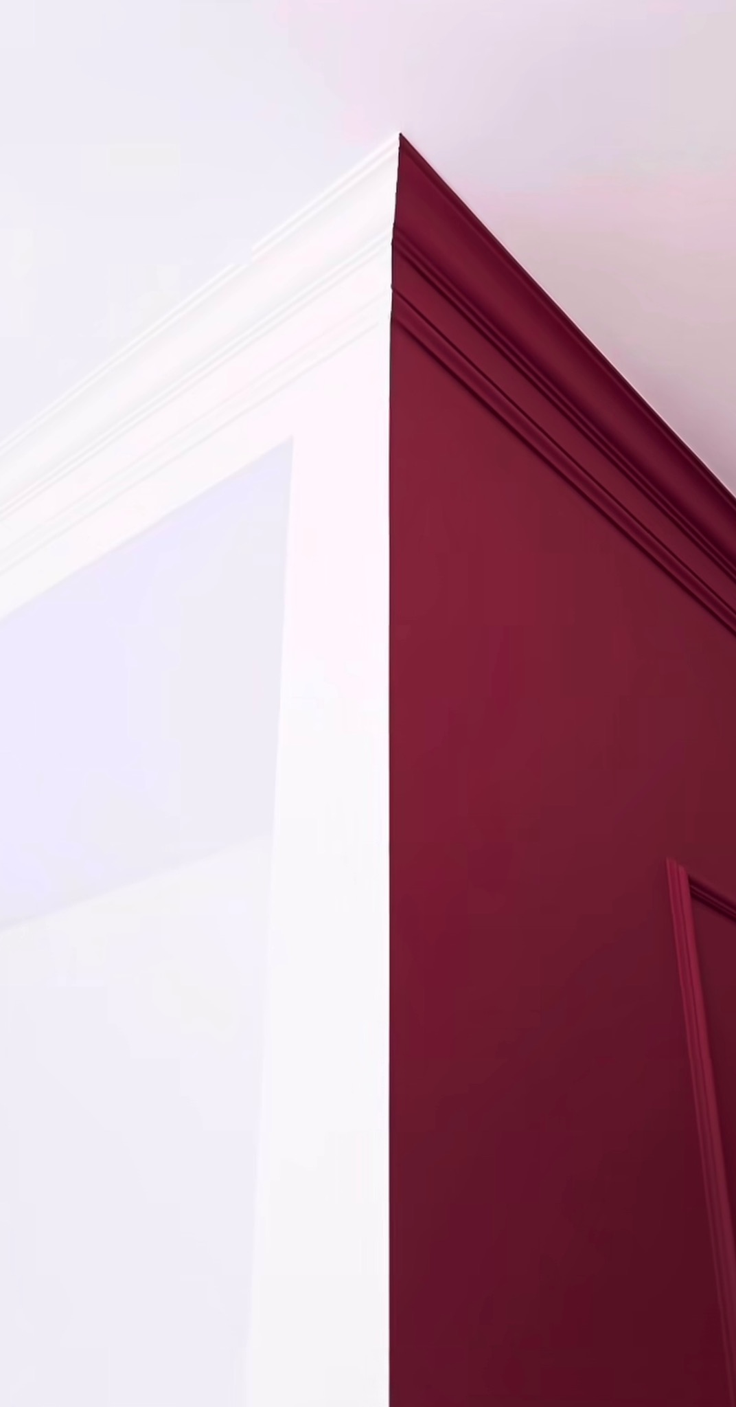 Ściana pomalowana na biało i bordowo z dekoracyjnymi listwami. Kontrast kolorów i detali architektonicznych. Wykończenie wnętrza w zbliżeniu.