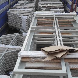 Bogusław Pytel BP Company - Transport metalowych ram konstrukcyjnych wewnątrz naczepy, zabezpieczonych folią i kartonem, z widoczną sylwetką osoby w odblaskowej kamizelce.