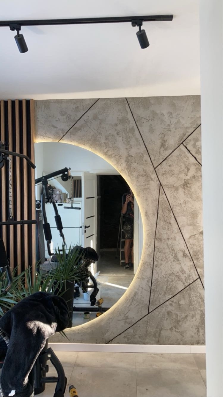 Nowoczesne wykończenie ściany z okrągłym lustrem z podświetleniem LED, widoczne elementy siłowni i drewniane lamele. Dekoracyjna faktura ściany.