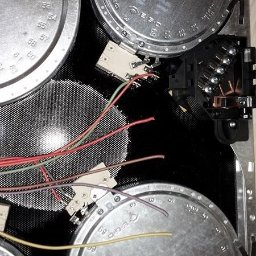 Józef Bujakowski - Wnętrze płyty indukcyjnej z widocznymi elementami grzejnymi, przewodami i modułem sterującym. Detal techniczny, ukazujący skomplikowaną budowę urządzenia.