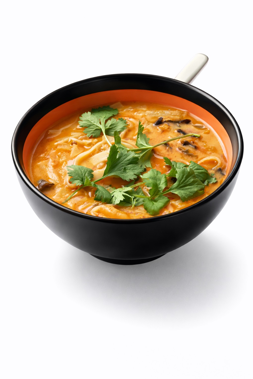 Aromatyczna zupa azjatycka w czarnej misce z pomarańczowym wnętrzem, udekorowana świeżą kolendrą. Idealna propozycja na ciepły posiłek.