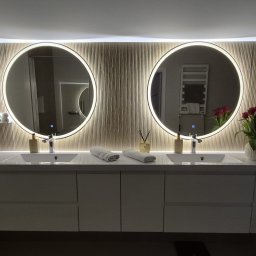 SPACE CONCEPT- PROJEKTOWANIE WNĘTRZ JOANNA MACIEJEWSKA - Nowoczesna łazienka z podwójną umywalką, okrągłymi lustrami z podświetleniem LED i dekoracyjną ścianą z pionowych paneli. Minimalistyczny design, kwiaty w wazonie.