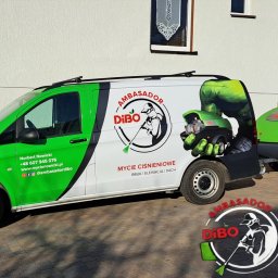 Mycie Nowicki Ambasador DiBO Norbert Nowicki - Zielono-biały van z logo firmy Dibo, specjalizującej się w myciu ciśnieniowym (bruk, elewacje, dachy), zaparkowany na kostce brukowej z przyczepą ze sprzętem.