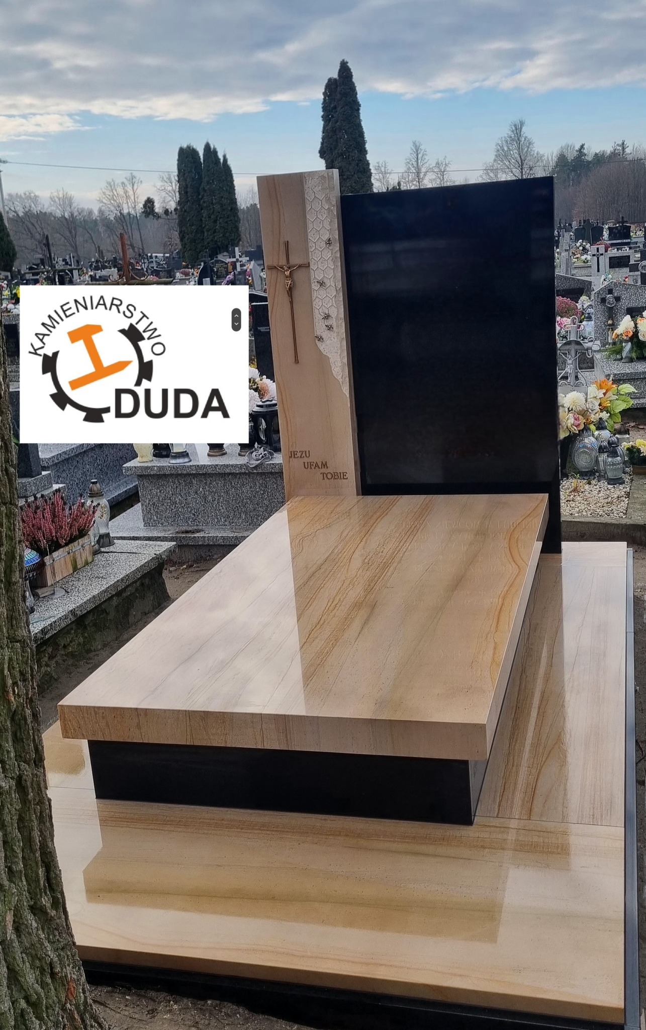 Nowoczesny nagrobek z piaskowca i czarnego granitu na cmentarzu. Jasny kamień z wyraźnym rysunkiem słojów. Krzyż na bocznej płycie. Napis: Jezu ufam Tobie.