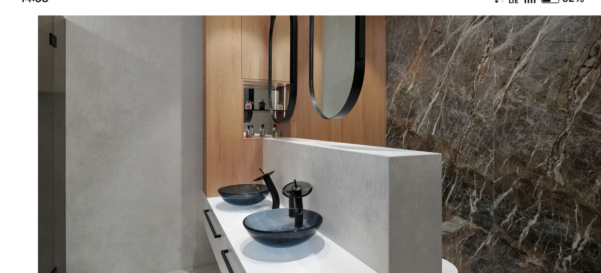 Nowoczesna łazienka z dwoma szklanymi umywalkami, marmurową ścianą i drewnianą szafką z lustrami w czarnych ramach. Minimalistyczny design i eleganckie wykończenie.