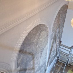 Remonty wykonczenia Krzysztof Barciszewski - Dekoracyjne malowanie ścian z efektem marmuru w klatce schodowej w Poznaniu. Widoczna drabina i zabezpieczone schody.