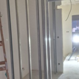 Remonty wykonczenia Krzysztof Barciszewski - Konstrukcja ścianki działowej z profili metalowych w trakcie montażu. Widoczna drabina i surowy stan wnętrza. Prace przygotowawcze do zabudowy.