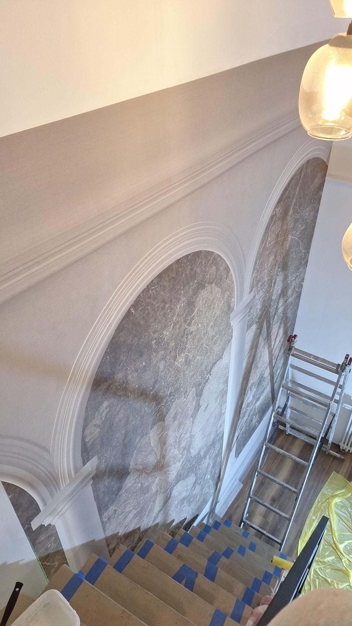 Dekoracyjne malowanie ścian z efektem marmuru w klatce schodowej w Poznaniu. Widoczna drabina i zabezpieczone schody.