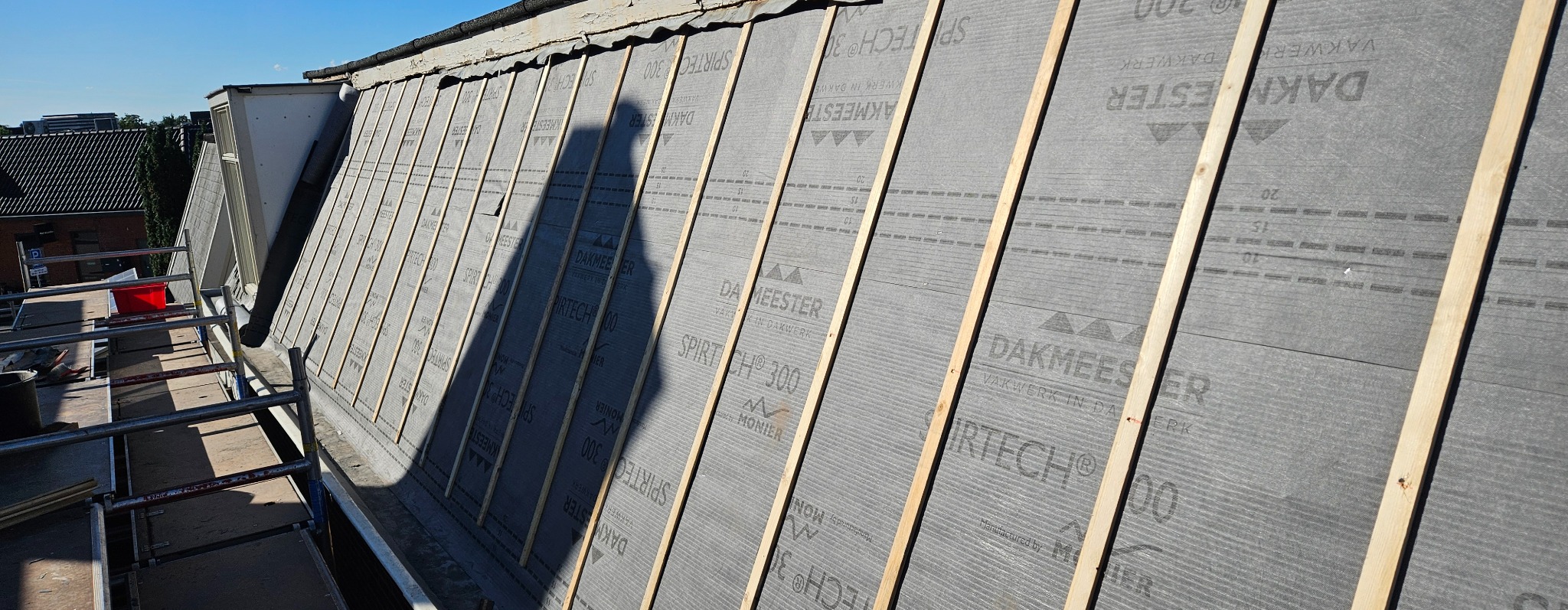 Dach z membraną DAKMEESTER SPIRTECH 300 i łatami drewnianymi, widok z rusztowania. Etap przygotowania do krycia dachu, w słoneczny dzień.