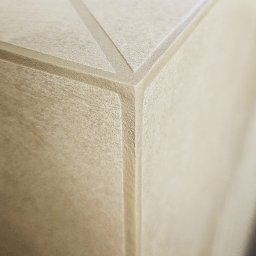 Ikona Lab Monika Stolarska - Detal narożnika ściany z dekoracyjną, geometryczną fakturą. Jasny, neutralny odcień. Precyzyjne wykonanie, widoczne linie i krawędzie. Minimalistyczny design.