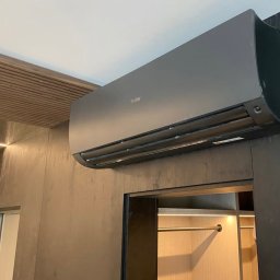 Wentica Tomasz Manowski - Zamontowany, grafitowy klimatyzator Haier w nowoczesnym wnętrzu z drewnianymi akcentami i oświetleniem LED. Widok z dołu, podkreślający minimalistyczny design.