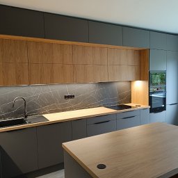 Karol Dyduch - Nowoczesna kuchnia z szarymi szafkami dolnymi i drewnianymi górnymi, marmurowym blatem i wyspą. Minimalistyczny design z oświetleniem LED pod szafkami.