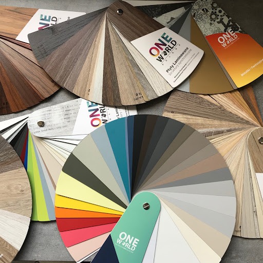 Paleta kolorów i struktur laminatów One World, prezentująca szeroki wybór odcieni drewna, metalików i barw jednolitych. Próbki ułożone wachlarzowo na szarym tle.