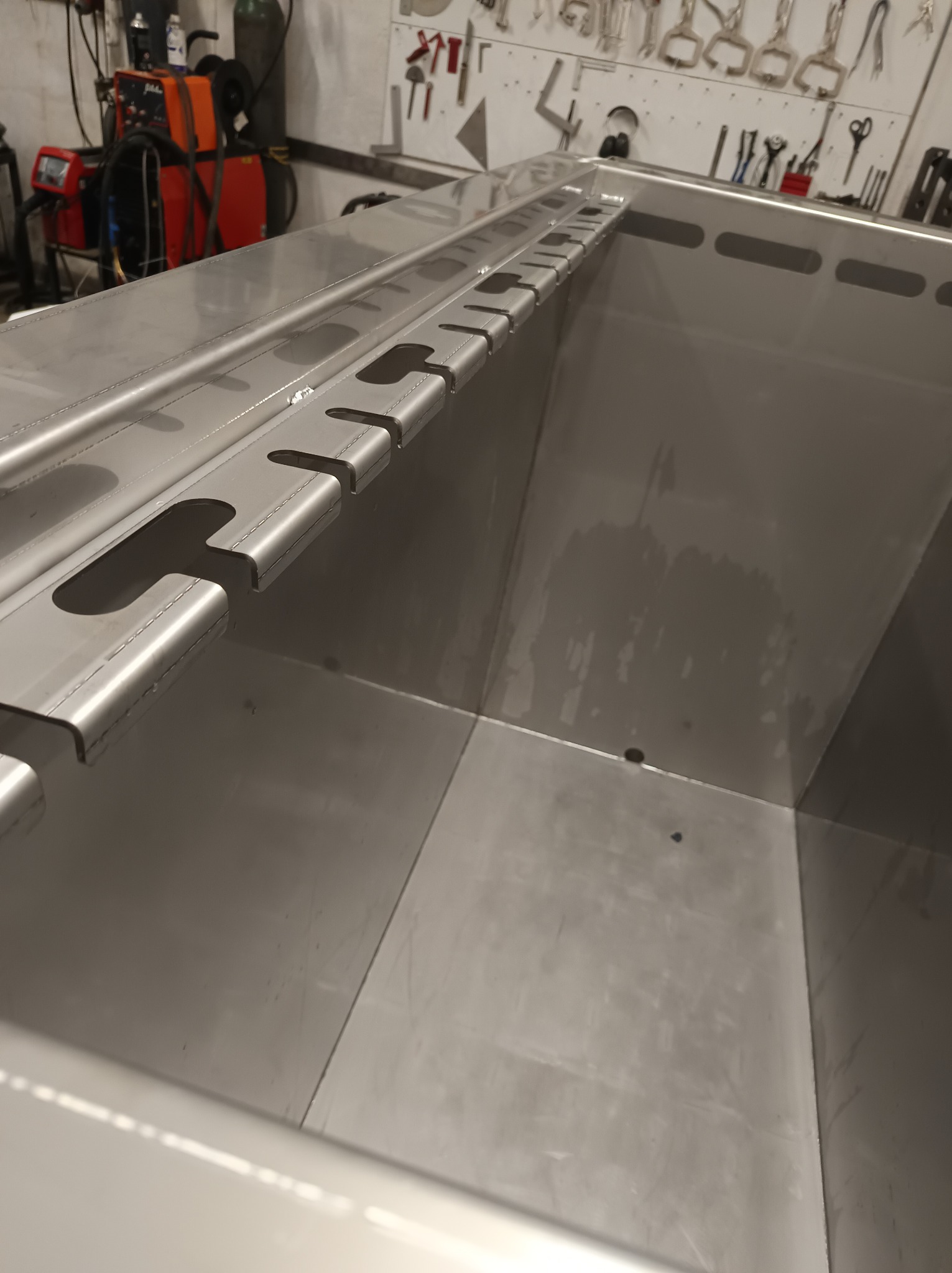 Metalowa konstrukcja z wyciętymi otworami, spawana, w warsztacie. Widoczne narzędzia i spawarka w tle. Szlifowana powierzchnia, precyzyjne wykonanie.