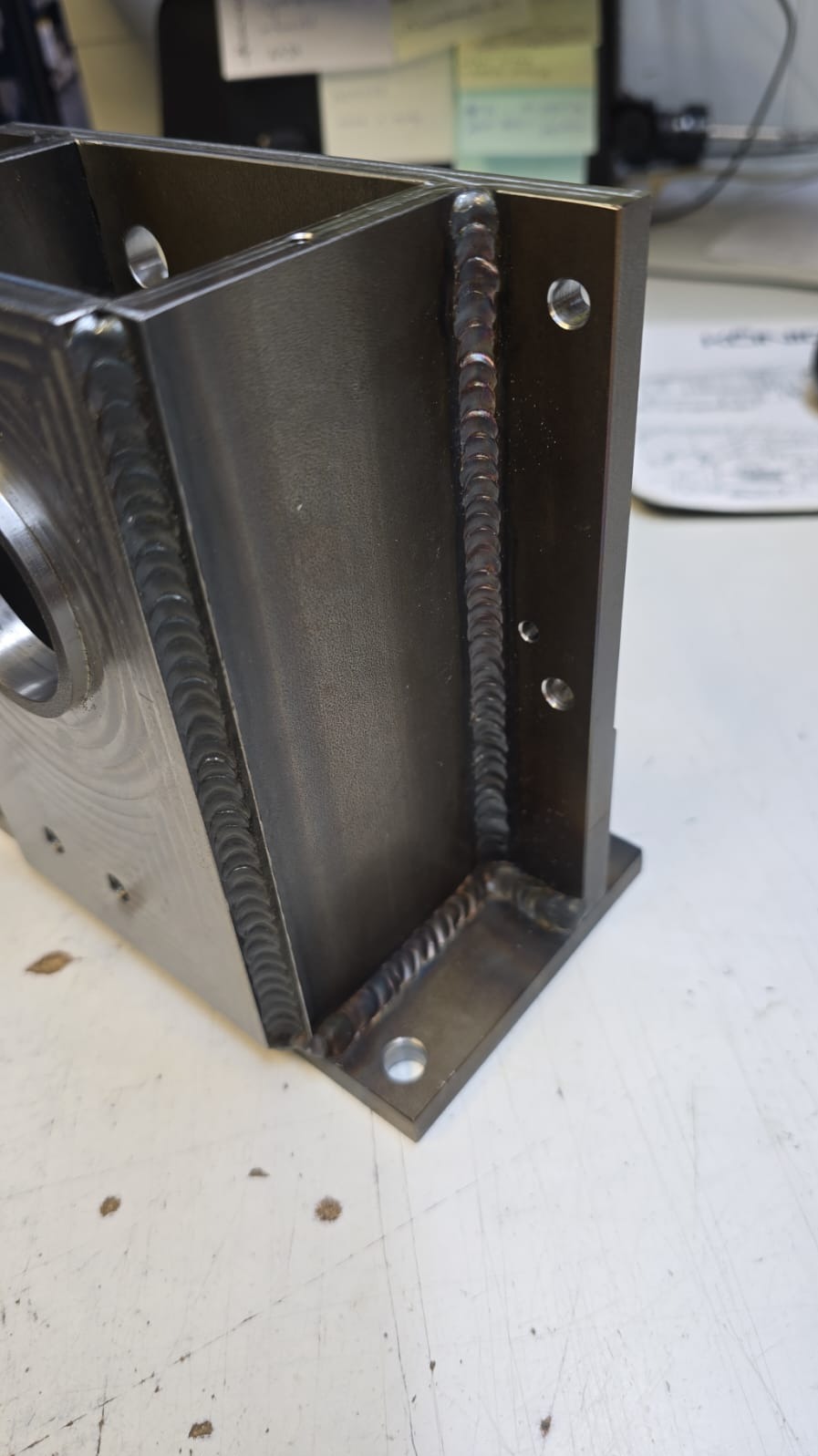 Metalowa konstrukcja spawana z widocznymi otworami, prezentująca precyzyjne spawy i solidne połączenia elementów. Detal obróbki metalu na jasnym tle.