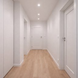 Bud-Max.Air Yurii Tepliuk - Biały korytarz z drewnianą podłogą, oświetleniem punktowym i trzema parami drzwi. Minimalistyczny design, świeżo po remoncie, widok z perspektywy.