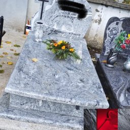 Kamieniarstwo Artystyczne Jacek Kociołek - Jasnoszary nagrobek z krzyżem i kwiatami, wykonany z kamienia o wyraźnej fakturze. Widoczny napis 'Spoczywaj w pokoju'. W tle inne nagrobki i jesienne liście.