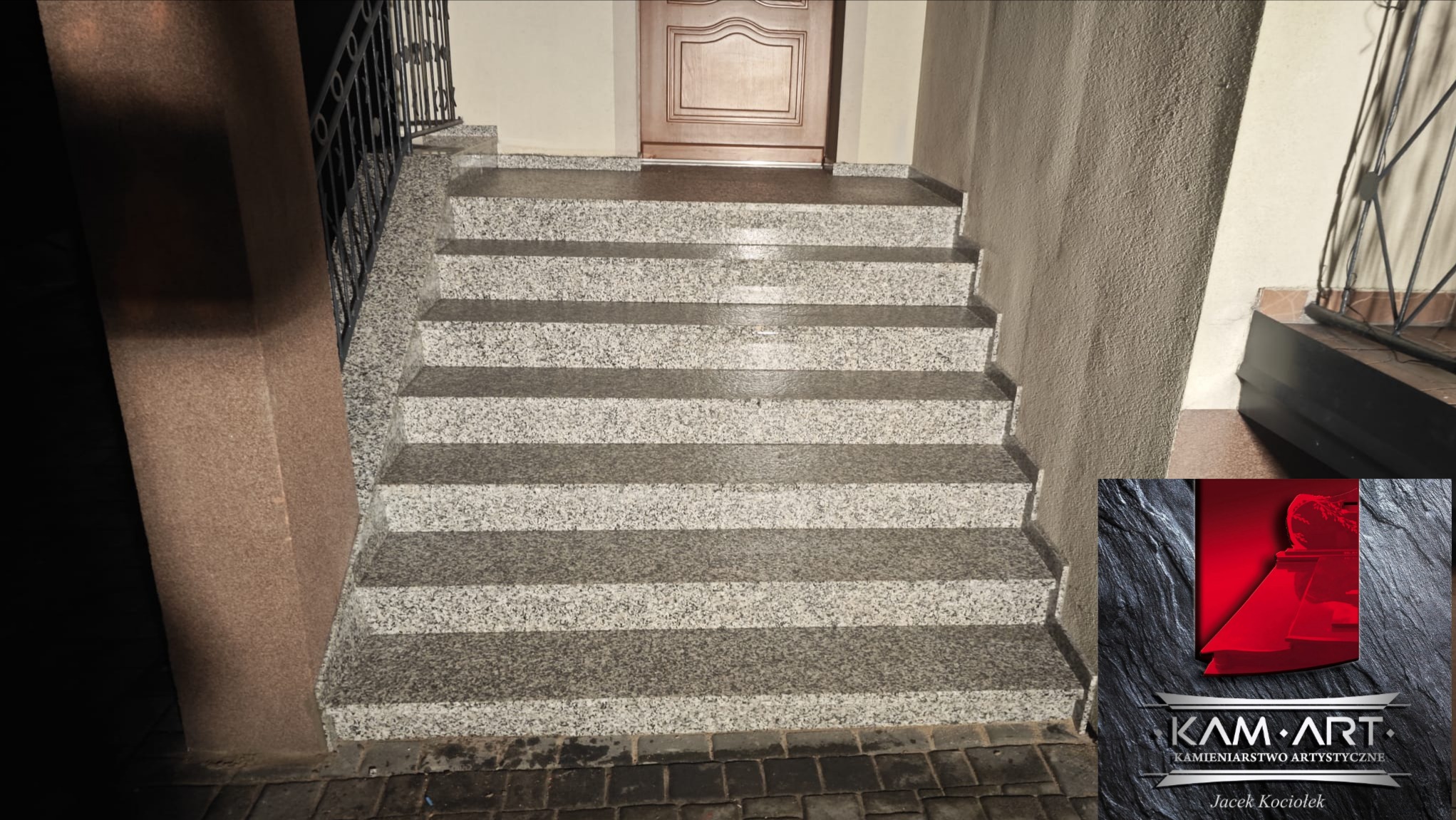 Zewnętrzne schody z szarego kamienia z balustradą prowadzące do drzwi wejściowych. Widoczny fragment logo firmy kamieniarskiej w prawym dolnym rogu.