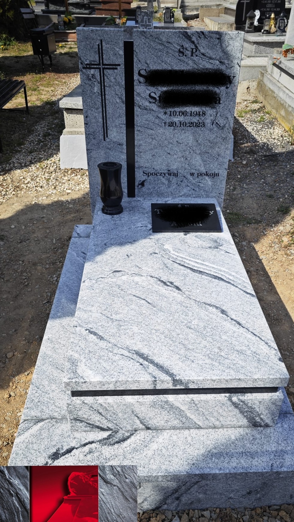 Jasnoszary nagrobek z granitu z czarnym krzyżem i wazonem, na cmentarzu. Widoczny napis 'Spoczywaj w pokoju' i daty. Charakterystyczny wzór kamienia.