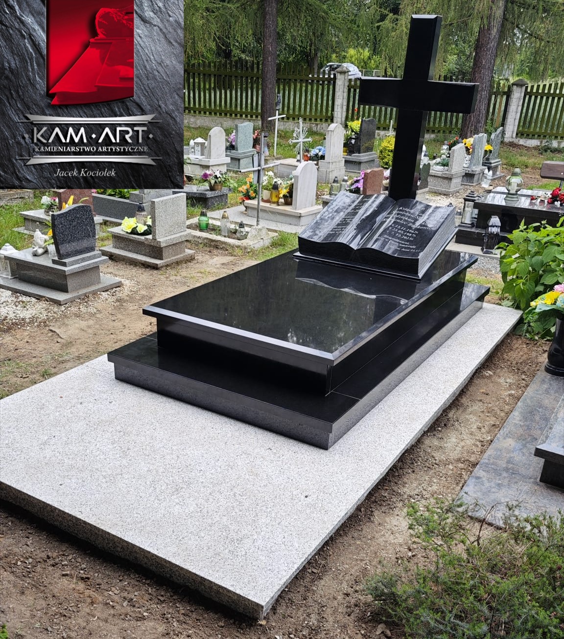 Czarny, podwójny nagrobek z otwartą księgą i krzyżem na cmentarzu, otoczony zielenią i innymi nagrobkami. Widoczny logotyp firmy.