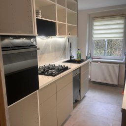 WARM HOME Adrian Laskowski - Jasna kuchnia z białymi szafkami bez frontów, marmurowym backsplashiem i czarnym zlewem. Widoczna płyta gazowa i piekarnik. Minimalistyczny design, neutralna kolorystyka.