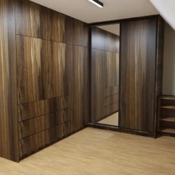 WARM HOME Adrian Laskowski - Brązowa szafa wnękowa z lustrem na poddaszu, drewnopodobne wykończenie, minimalistyczny design, oświetlenie sufitowe.