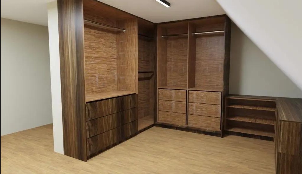 Drewniana szafa wnękowa z szufladami i drążkami na ubrania, dopasowana do skosu dachu. Widoczna tekstura drewna i oświetlenie sufitowe.