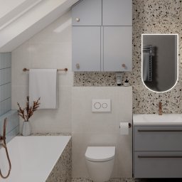 Materna Design - Stylowa aranżacja łazienki na poddaszu w Koniuszy. Umywalka z szafką, toaleta, wanna z armaturą w kolorze miedzi i lustro z podświetleniem LED.