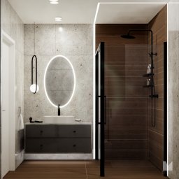 Materna Design - Nowoczesna łazienka z owalnym lustrem LED, szarą szafką pod umywalką i kabiną prysznicową z ciemnego drewna. Minimalistyczny design, ciepłe oświetlenie.