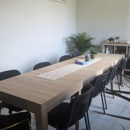 DLF PLACE sp. z o.o. - Jasne biuro po sprzątaniu: duży stół konferencyjny z dekoracjami, krzesła, regał z ozdobami, roślina doniczkowa. Czysta przestrzeń gotowa do pracy.