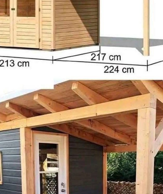 Drewniana konstrukcja z wymiarami, prawdopodobnie altana lub domek narzędziowy z szarymi ścianami i jasnym dachem, częściowo widoczna na tle zieleni.