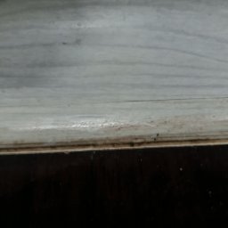 Patrycja Simińska - Zacieki i brud na marmurowym parapecie okiennym, widoczne ślady po niedokładnym umyciu. Dolna część okna w ciemnym kolorze. Niewyraźne zdjęcie.