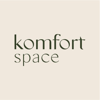 Logo 'komfort space' w kolorze ciemnej zieleni na beżowym tle. Minimalistyczny font, nazwa firmy w dwóch wierszach, nowoczesny design.