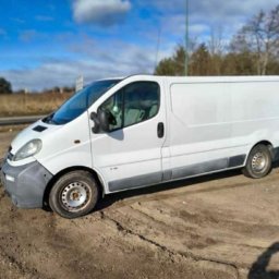 Jan Jaworski - Biały samochód dostawczy Opel Vivaro na piaszczystym podłożu, widok z boku, błękitne niebo w tle. Auto gotowe do transportu, np. podczas przeprowadzki.