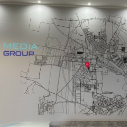 Daniel Wrona Druk na Ścianach - Ściana biura z logo 'BD Media Group' i mapą miasta z czerwoną pinezką. Nowoczesny design wnętrza, jasne oświetlenie, minimalistyczny styl.