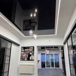 StretchDom-sufity napinane - Nowoczesne wnętrze z czarnym, lustrzanym sufitem podwieszanym i oświetleniem LED. Widoczne szklane lampy wiszące i przesuwne drzwi.