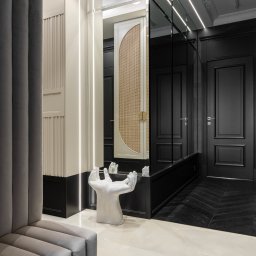 SCM SPÓŁKA Z OGRANICZONĄ ODPOWIEDZIALNOŚCIĄ - Elegancki przedpokój z lustrzaną szafą, oświetleniem LED i dekoracyjną rzeźbą dłoni. Kontrast bieli i czerni, parkiet w jodełkę, marmurowe płytki podłogowe.