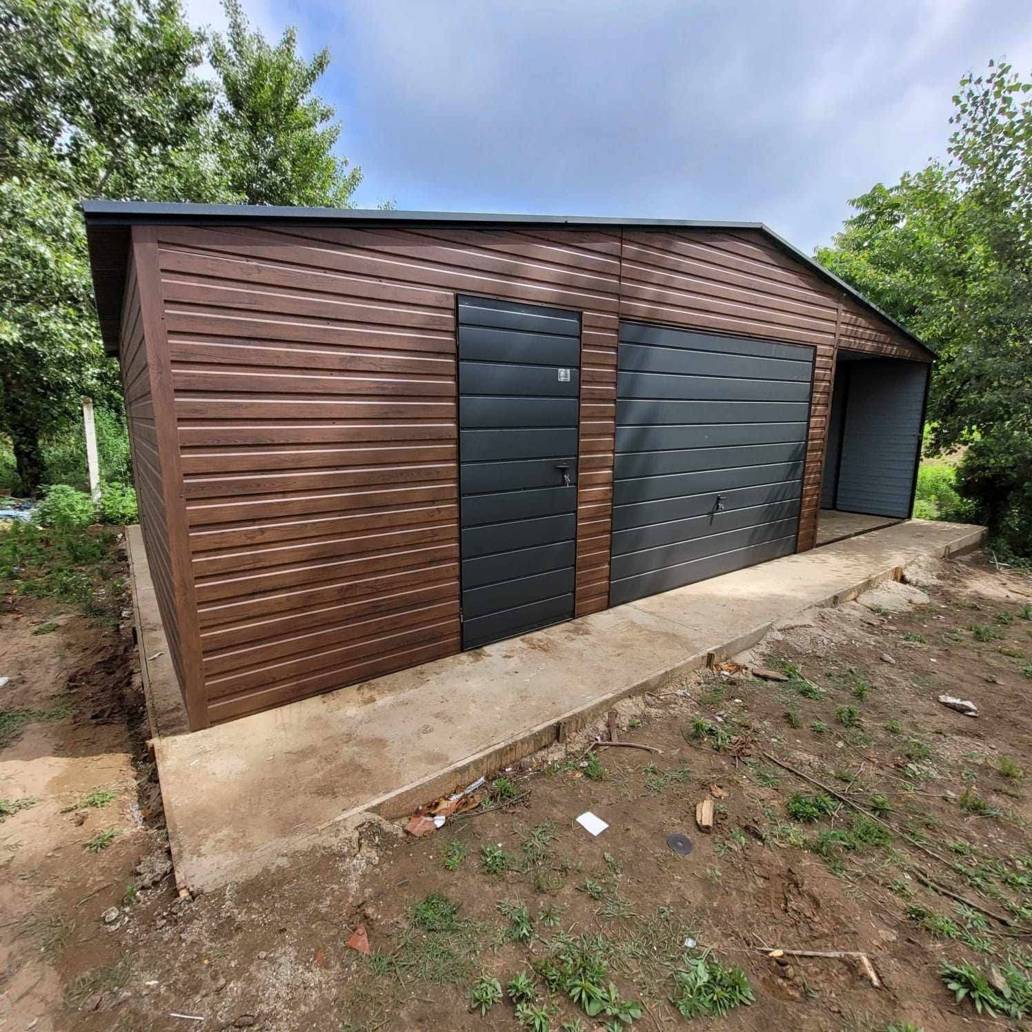 Garaż blaszany z brązową elewacją imitującą drewno i szarą bramą segmentową oraz drzwiami wejściowymi, na betonowej wylewce, otoczony zielenią.