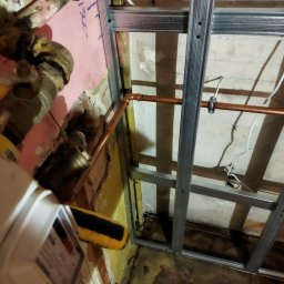 Tyzon Victor Tyszlewicz - Montaż instalacji wodnej z miedzianych rur i metalowej konstrukcji podwieszanego sufitu w trakcie prac remontowych. Widoczne elementy instalacji gazowej i wodomierz.